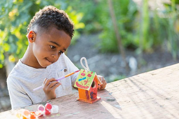 Little boy (5 years) painting bird house.